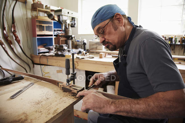 Людина працює над дерев'яним бантом — стокове фото
