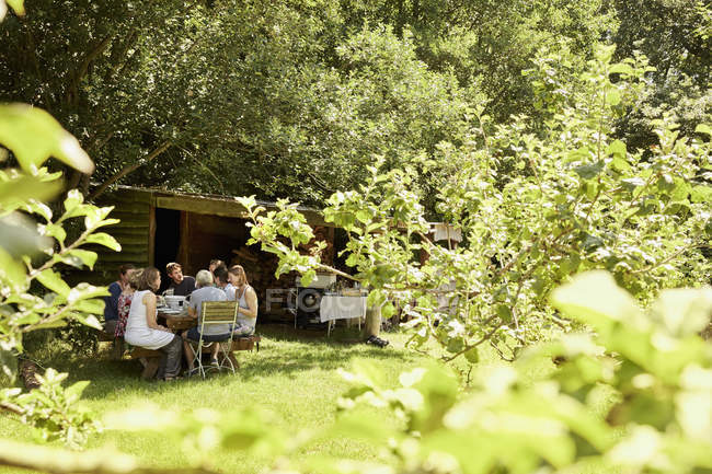 Group of people in shade of trees in garden. — Stock Photo