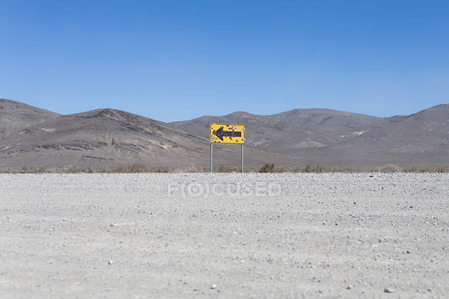 Señal de flecha acribillada en el desierto - foto de stock
