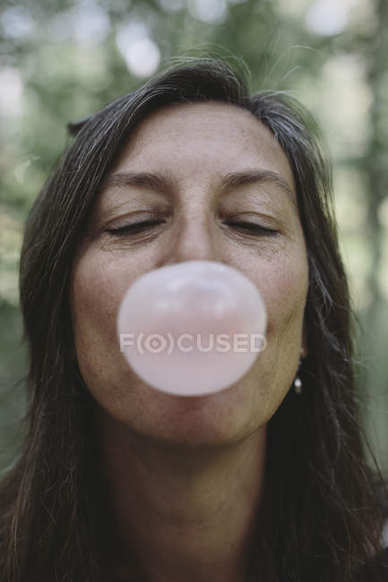 Женщина надувает пузырь жвачки — стоковое фото