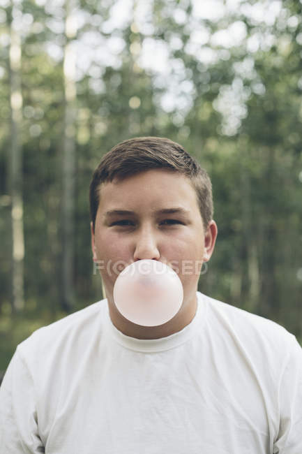 Мальчик надувает пузырь жвачки — стоковое фото
