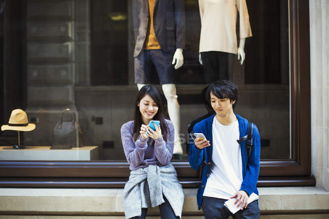 Молодые мужчина и женщина с помощью смартфонов — стоковое фото