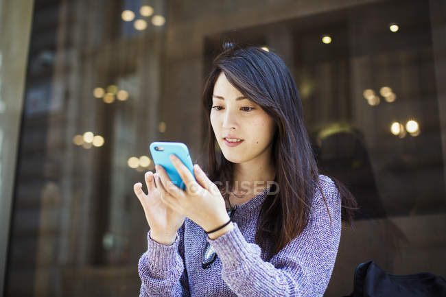 Joven mujer japonesa usando smartphone - foto de stock