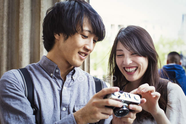 Japanese man and woman holding camera — Stock Photo