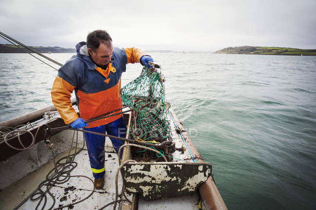 Fisherman opening  fishing creel — Stock Photo