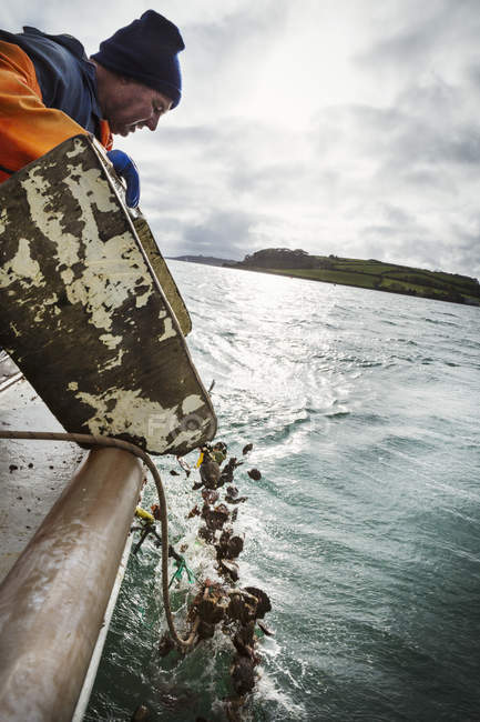 Pescatore ribaltamento gusci vuoti in acqua — Foto stock