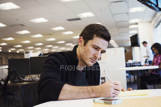 Чоловік сидить за столом і пише — стокове фото