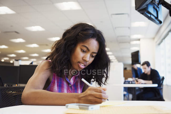 Frau sitzt am Tisch und schreibt — Stockfoto