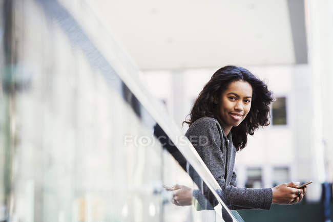 Mujer inclinada sobre riel de balcón - foto de stock