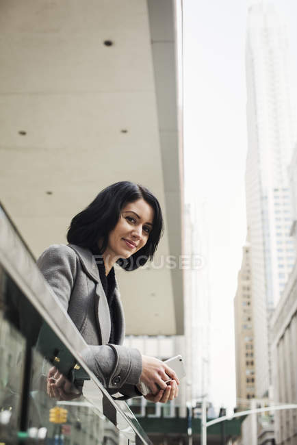 Woman leaning over balcony and holding cellphone — Stock Photo