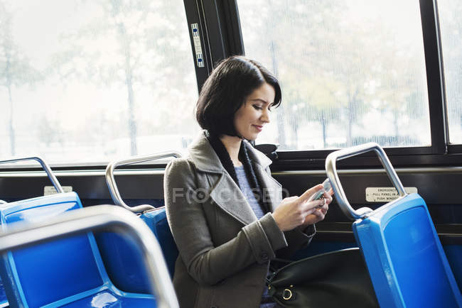 Woman sitting on train with cellphone — Stock Photo