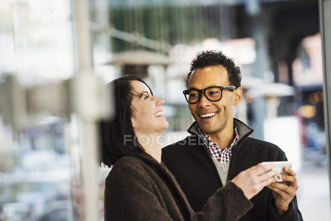 Uomo e donna che tengono il cellulare e ridono — Foto stock