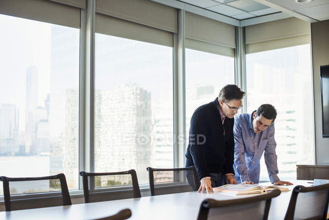 Men standing at table and looking at book — Stock Photo