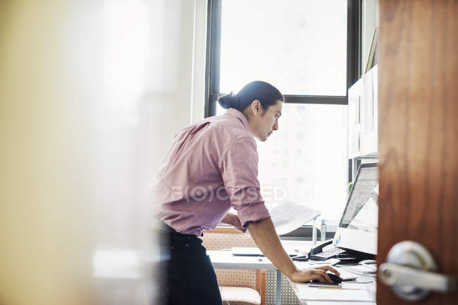 Man standing in office and leaning on desk — Stock Photo