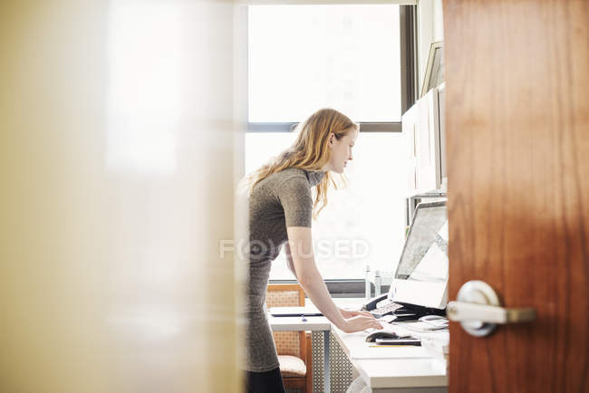 Mujer de pie y utilizando el ordenador portátil - foto de stock