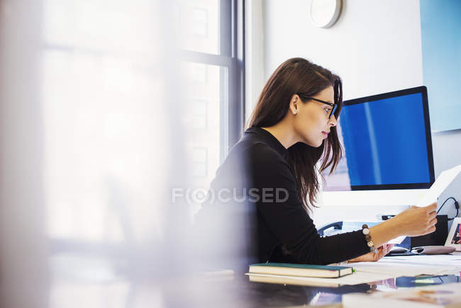 Mujer sentada en el escritorio en la oficina - foto de stock