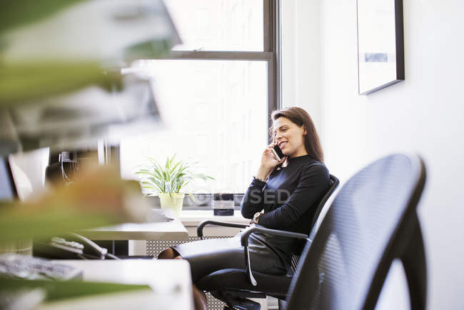 Mujer sentada en el escritorio en la oficina - foto de stock