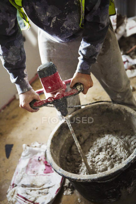 Builder mixing plaster using an electric mixer — Stock Photo