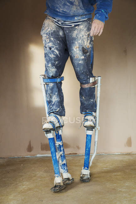 Plasterer wearing stilts — Stock Photo