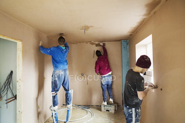 Three men at house under construction — Stock Photo