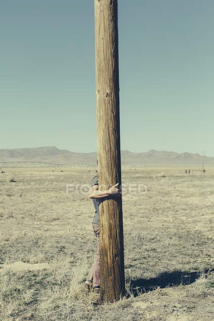 Homme avec ses bras autour du poteau en bois — Photo de stock
