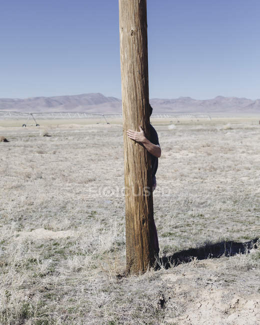 Чоловік з руками навколо дерев'яного полюса — стокове фото