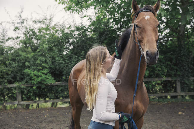 Женщина и скаковая лошадь в загоне — стоковое фото