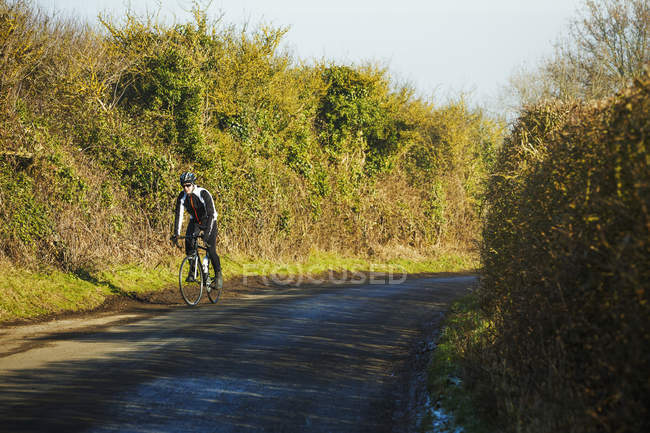 Ciclista equitação ao longo da estrada rural — Fotografia de Stock