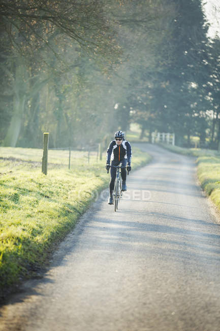 Cyclist pedaling along country road — Stock Photo