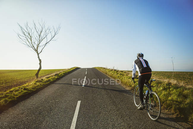 Cycliste le long de la route de campagne — Photo de stock