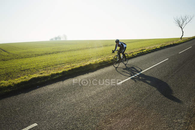 Ciclista equitação ao longo da estrada rural — Fotografia de Stock