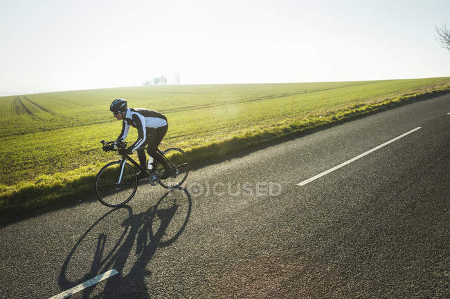 Ciclista a lo largo de la carretera del país - foto de stock