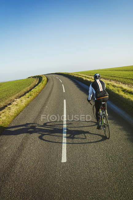 Cyclist pedaling along country road — Stock Photo