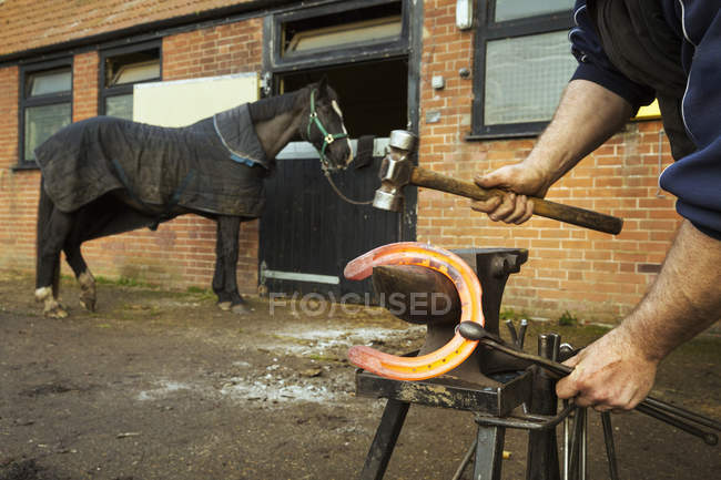 Contadino con pinze e martello per contenere ferro di cavallo — Foto stock