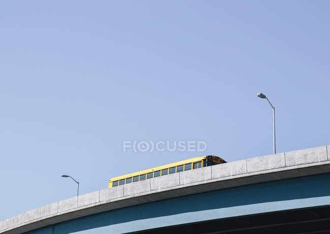 Schoolbus driving over an elevated roadway — Stock Photo