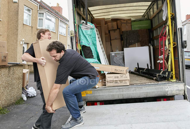 Two men lifting awkward package — Stock Photo