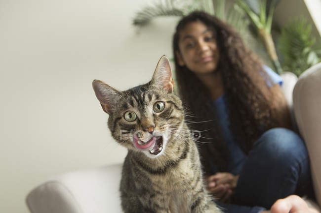 Girl sitting on sofa with pet cat — Stock Photo