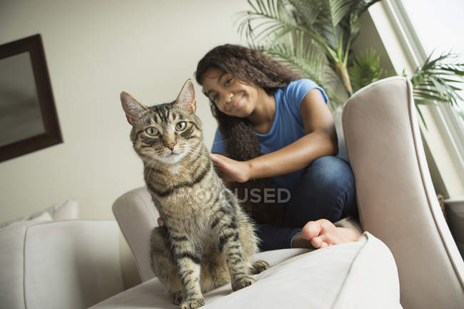 Girl sitting on sofa with cat — Stock Photo