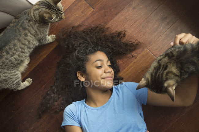 Chica acostada en su espalda acariciando gato - foto de stock