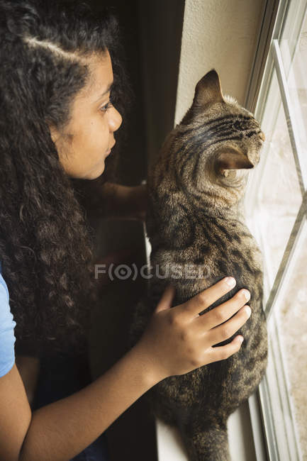 Mädchen mit Katze am Fenster — Stockfoto