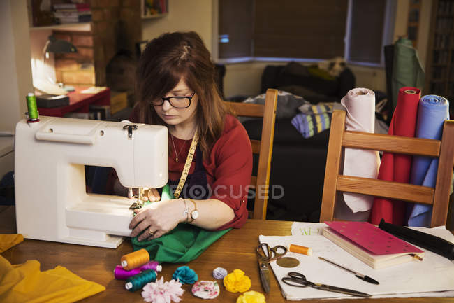Donna utilizzando macchina da cucire elettrica sul tavolo — Foto stock