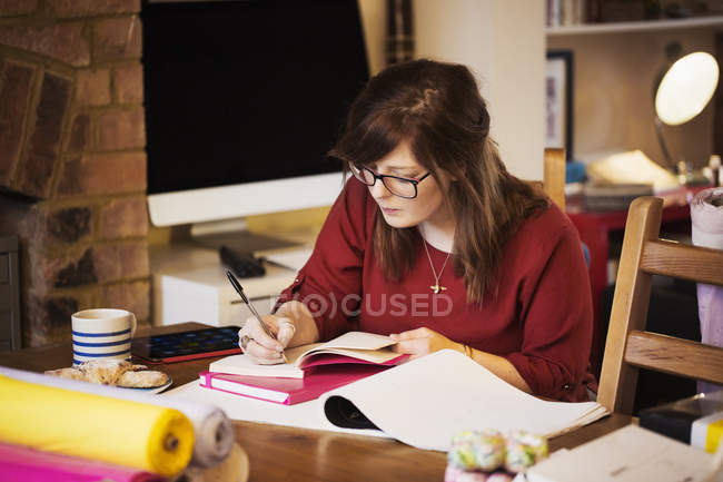 Frau sitzt am Tisch und macht sich Notizen — Stockfoto