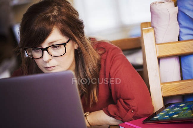 Женщина с помощью ноутбука склоняется к экрану — стоковое фото