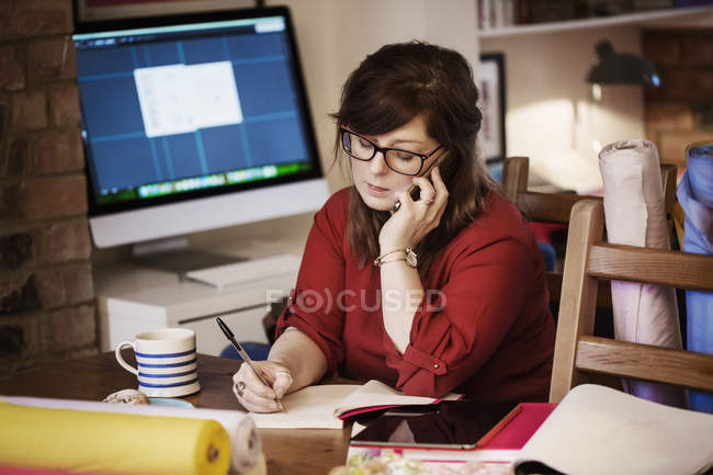 Frau benutzt Smartphone und macht sich Notizen mit Bleistift — Stockfoto