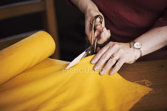 Woman dressmaking scissors to cut material — Stock Photo