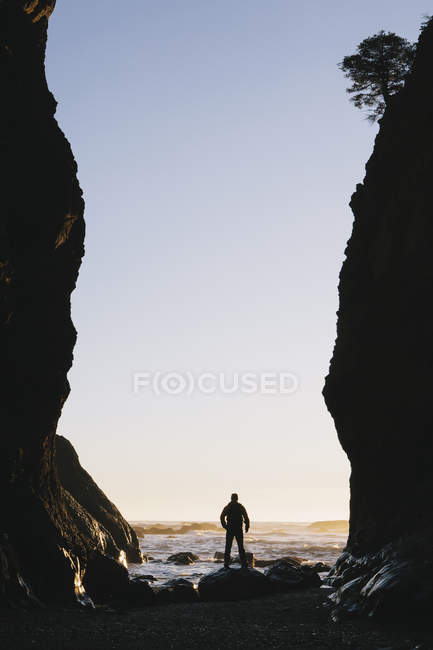 Чоловік стоїть між високими скелями в сутінках — стокове фото