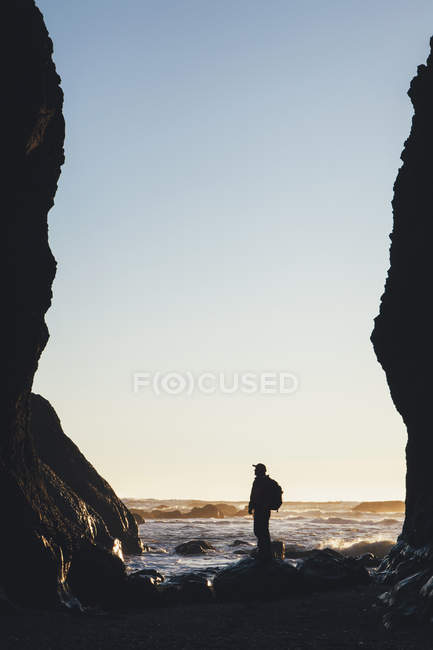 Человек, стоящий между высокими скалами в сумерках — стоковое фото