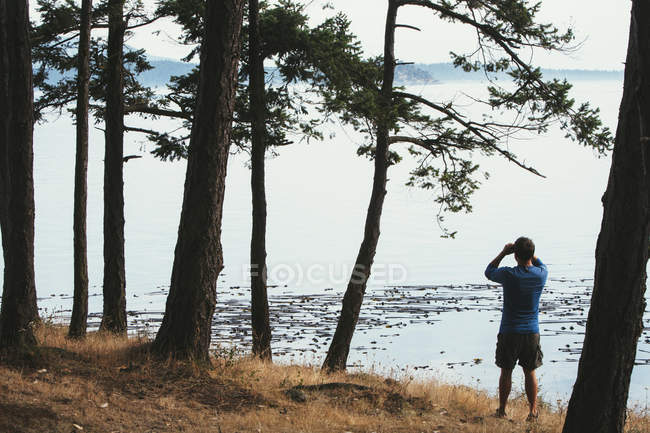 Homem em pé na praia e olhando através de binóculos — Fotografia de Stock