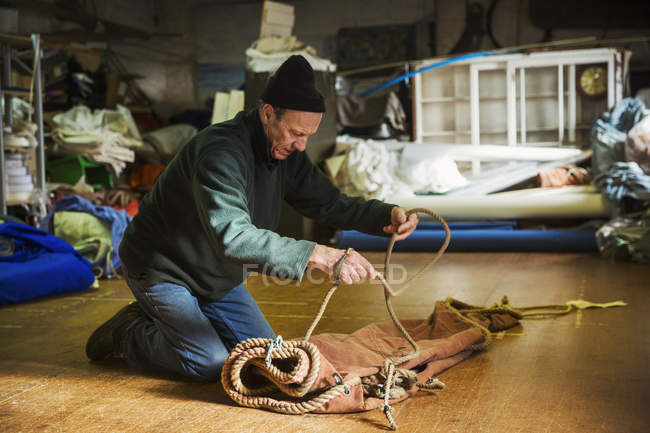 Человек вяжет верёвку на парусе . — стоковое фото
