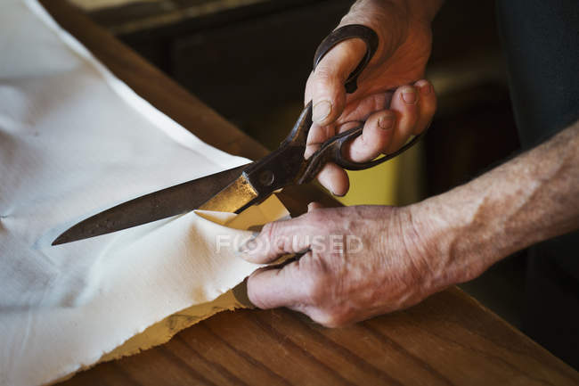 Mancutting piece of sailcloth — Stock Photo